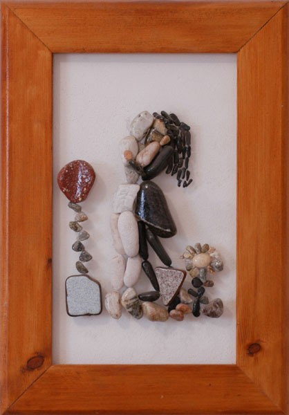 Pareja abrazada realizada con piedras naturales sobre plexiglás, acompañada por flores que evocan cariño y armonía.