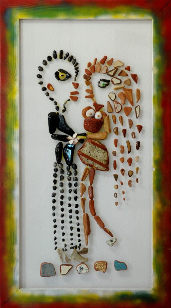 Due figure umane realizzate con pietre e frammenti ceramici su plexiglas si abbracciano mentre forme e colori iniziano a intrecciarsi, simboleggiando la nascita di un legame affettivo.
