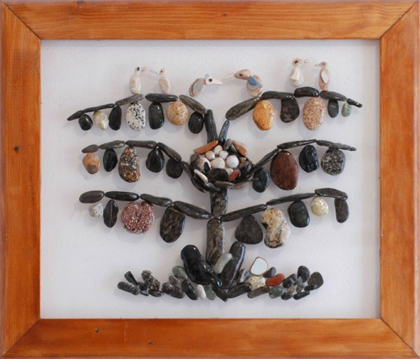 Árbol realizado con piedras naturales sobre plexiglás, con un gran nido lleno de huevos y aves posadas en sus ramas.