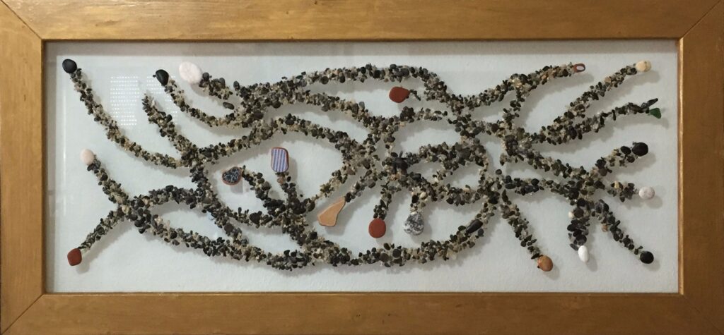 Composición abstracta realizada con arena, pequeñas piedras y fragmentos de cerámica sobre vidrio, formando una compleja red de caminos entrelazados.