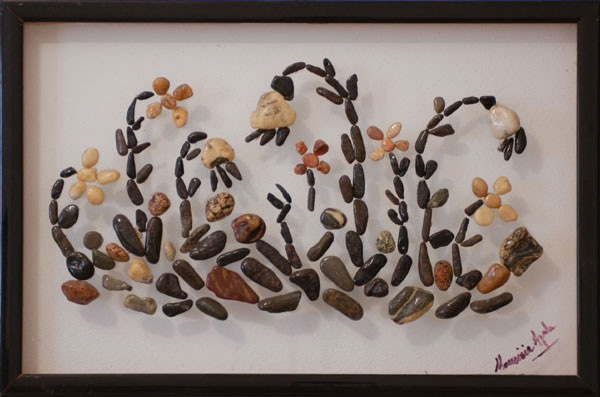 Plantas y flores silvestres realizadas con piedras naturales sobre plexiglás, formando una composición inspirada en la vegetación del campo.