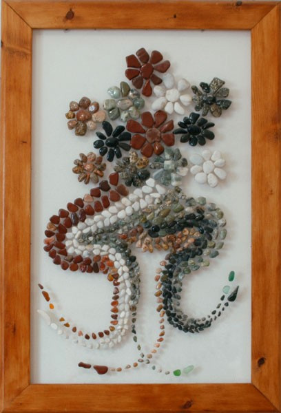 Composición floral realizada con piedras naturales de distintos colores sobre plexiglás, formando flores y curvas decorativas de inspiración imaginativa.