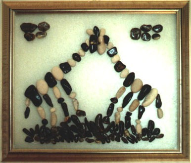 Dos jirafas realizadas con piedras naturales sobre vidrio, acercando sus cabezas en una escena de cariño y unión.