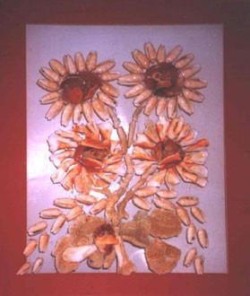 Girasoles realizados principalmente con conchas naturales sobre vidrio, formando una composición floral luminosa y decorativa.