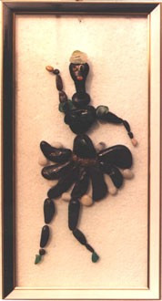 Figura de una bailarina realizada con piedras naturales sobre vidrio, representada en una elegante postura de danza.