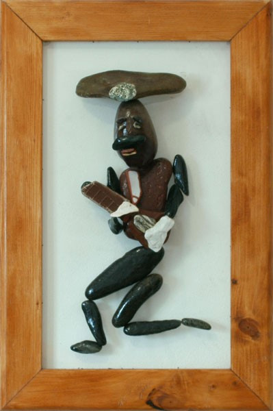 Figura humana tocando una guitarra, realizada con piedras naturales sobre plexiglás.