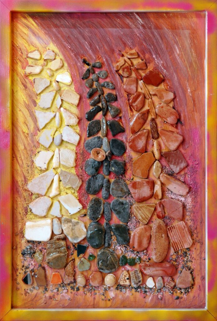 Composición abstracta realizada con piedras naturales sobre tablilla pintada, donde tres pinos estilizados se elevan en tonos claros, oscuros y rojizos sobre un fondo cálido.