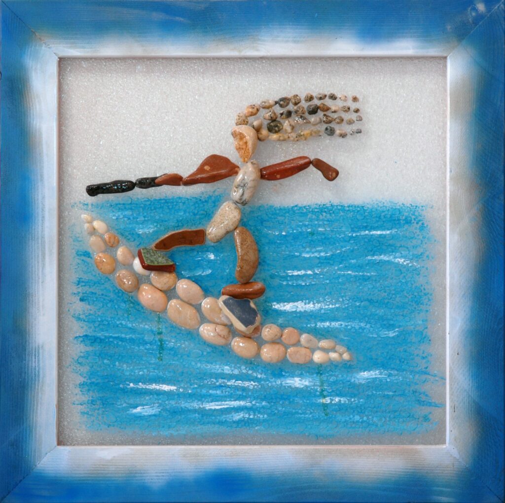 Composizione realizzata su plexiglas con pietre e frammenti di ceramica che raffigurano una persona mentre pratica surf su un'onda azzurra.