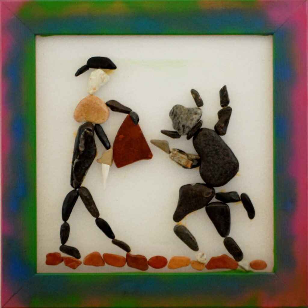 Figura realizzata con pietre e frammenti di ceramica su plexiglas che rappresenta un torero di fronte a un toro nell'istante della carica.